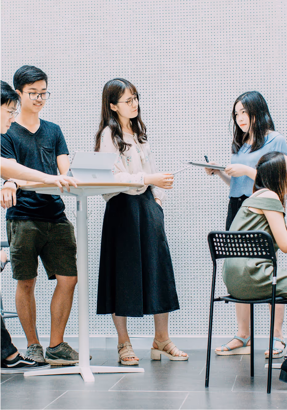 A group of four young adults gathered around a white table in a bright, modern office